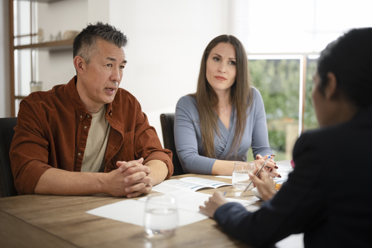 Two people talking to someone with documents in front of them