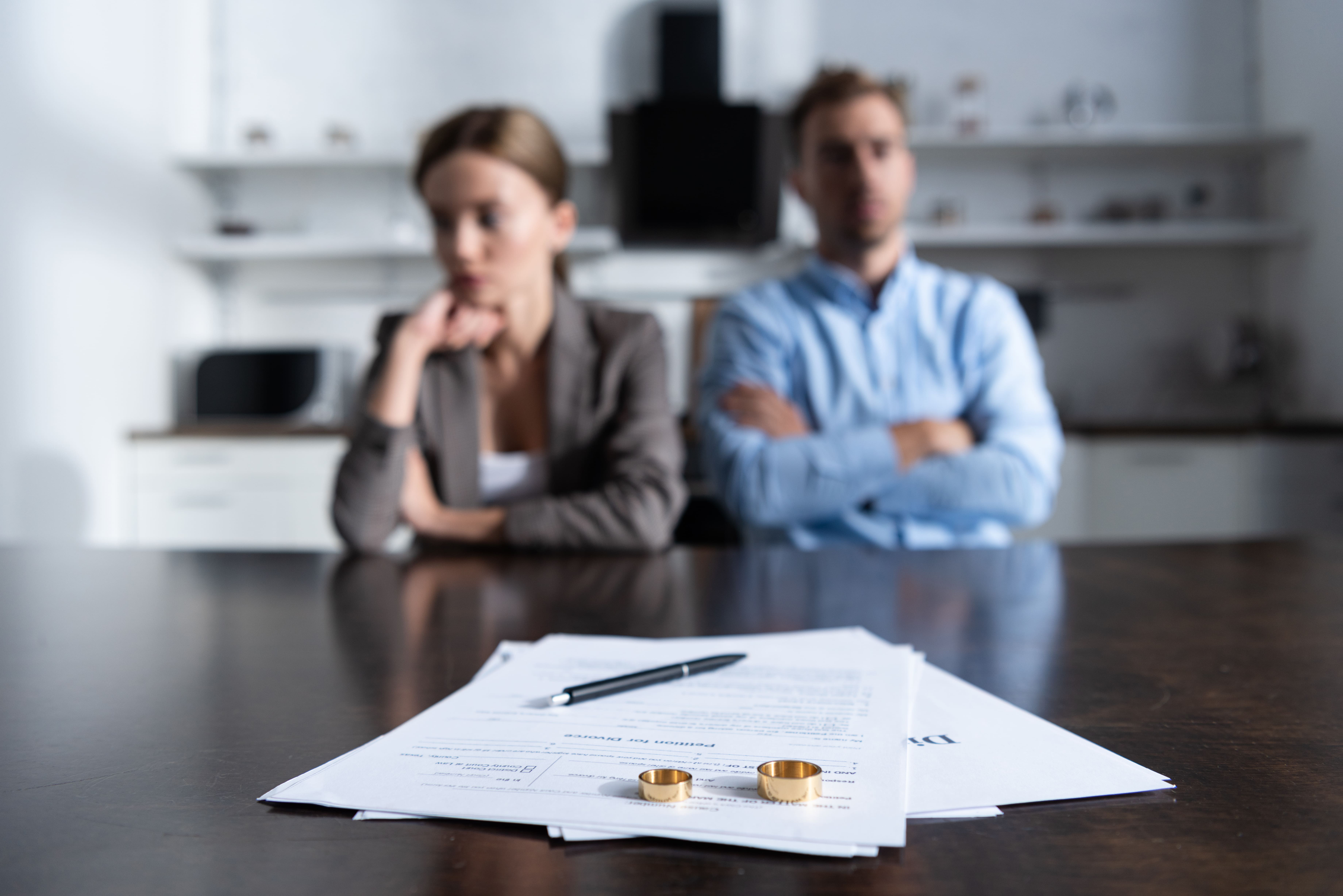 Couple sitting at table with divorce papers and rings