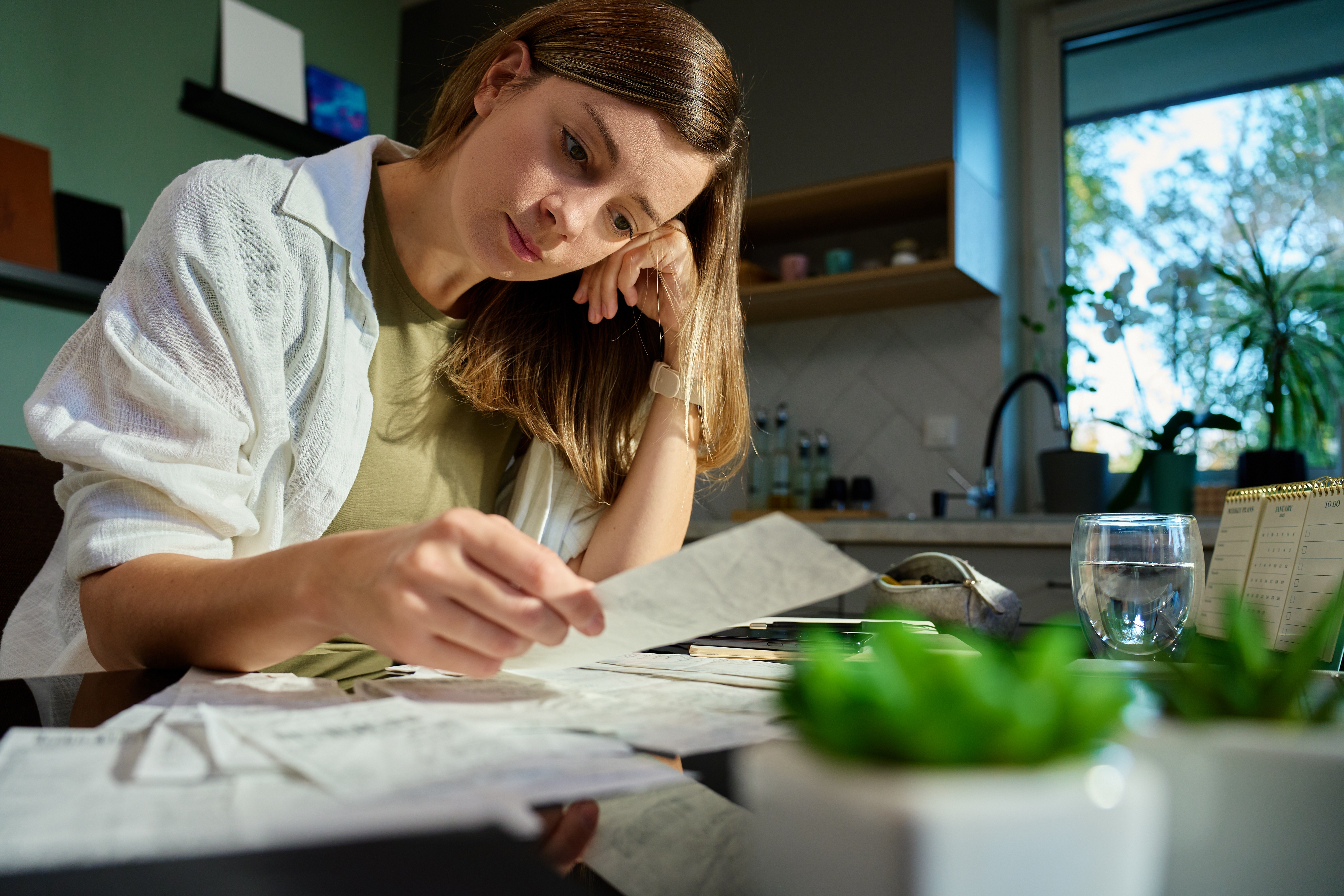 Woman reviewing bills at kitchen table