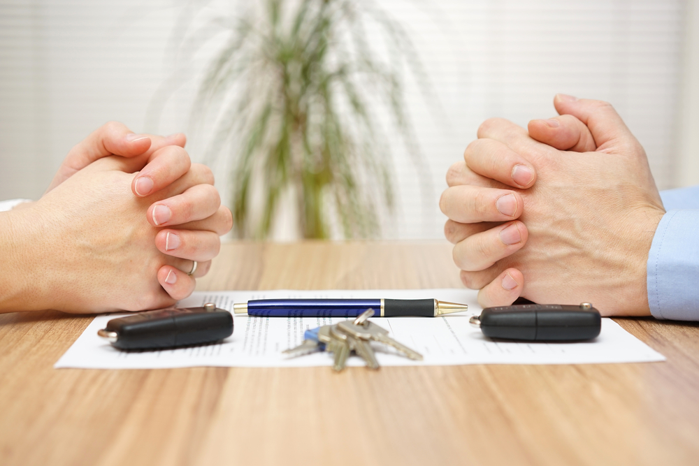 Couples hands looking at each other over divorce papers